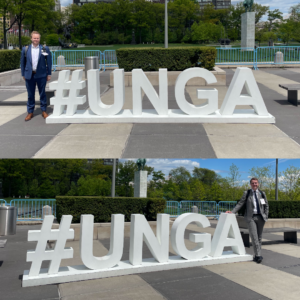 Cole Kelleher and Chris Carter standing by a large '#UNGA' sign